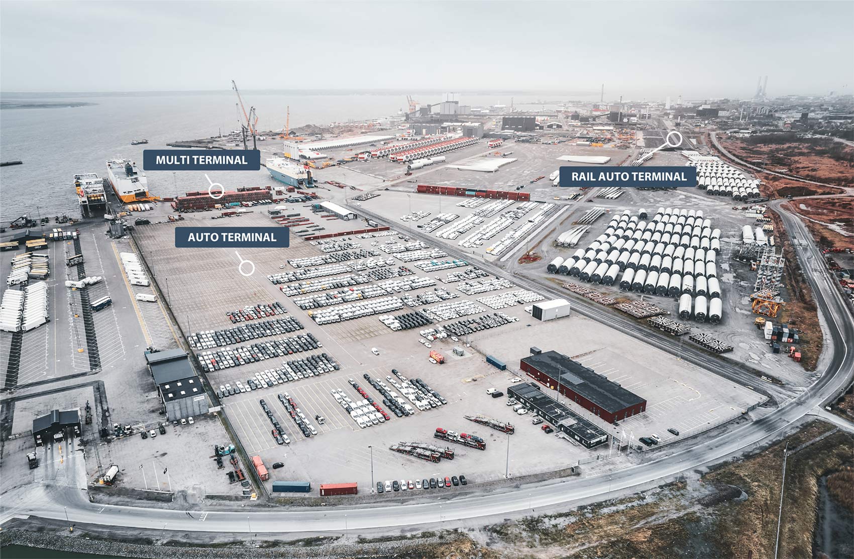 Drone still of SAL's three terminals, showcasing ongoing work on the new 835-meter double tracks, the entire auto terminal, and the multi-terminal with wind turbine components. The quay area, with three ships docked at the RoRo ramps, is also visible.